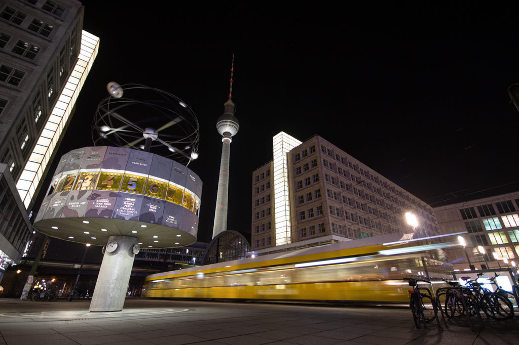 Alexanderplatz in Berlin bei Nacht mit Weltzeituhr und bewegungsunscharfe fahrende Straßenbahn