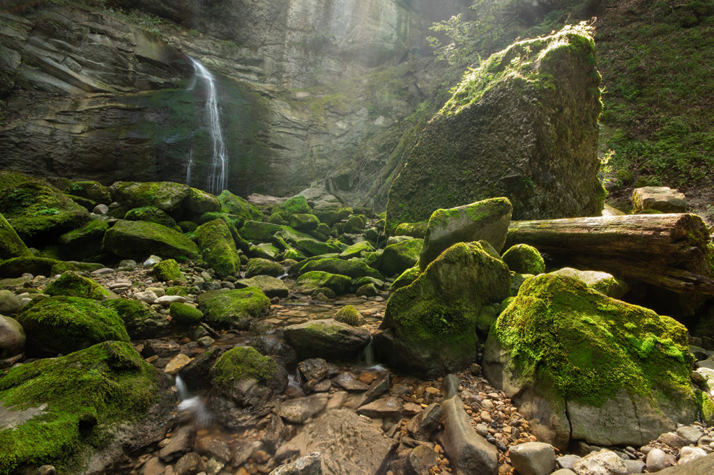 Kleiner Geschwender Wasserfall im Allgäu während Sommertrockenheit mit moosbewachsenen Steinen im Vordergrund