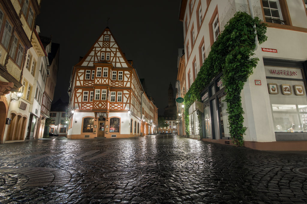 Mainzer Altstadt bei Nacht mit nassen spiegelnden Pflastersteinen im Vordergrund