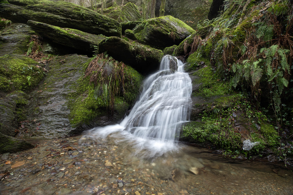 Wasserfall fließt von rechts nach links im Bild einen Felsen hinunter