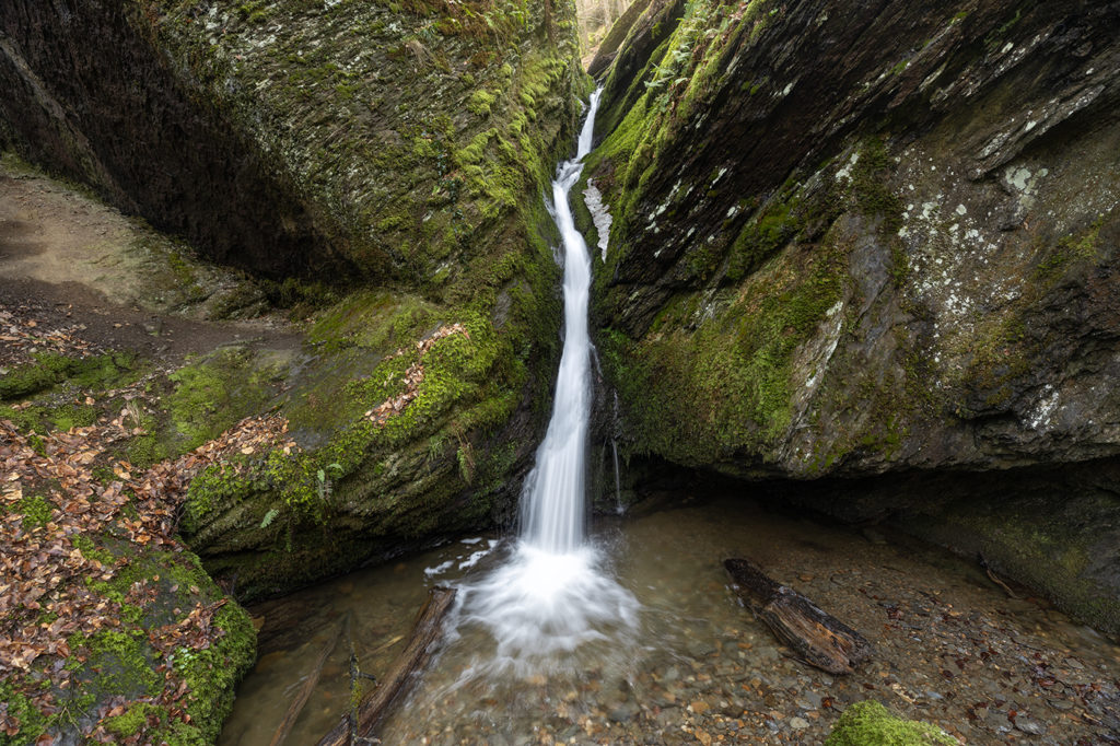 Wasserlauf in Felsschlucht zwischen zwei mit Moos bewachsenen Felsen