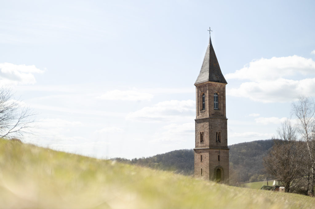 einsamer Glockenturm in Falkenstein in der Pfalz mit unscharfer Wiese im Vordergrund