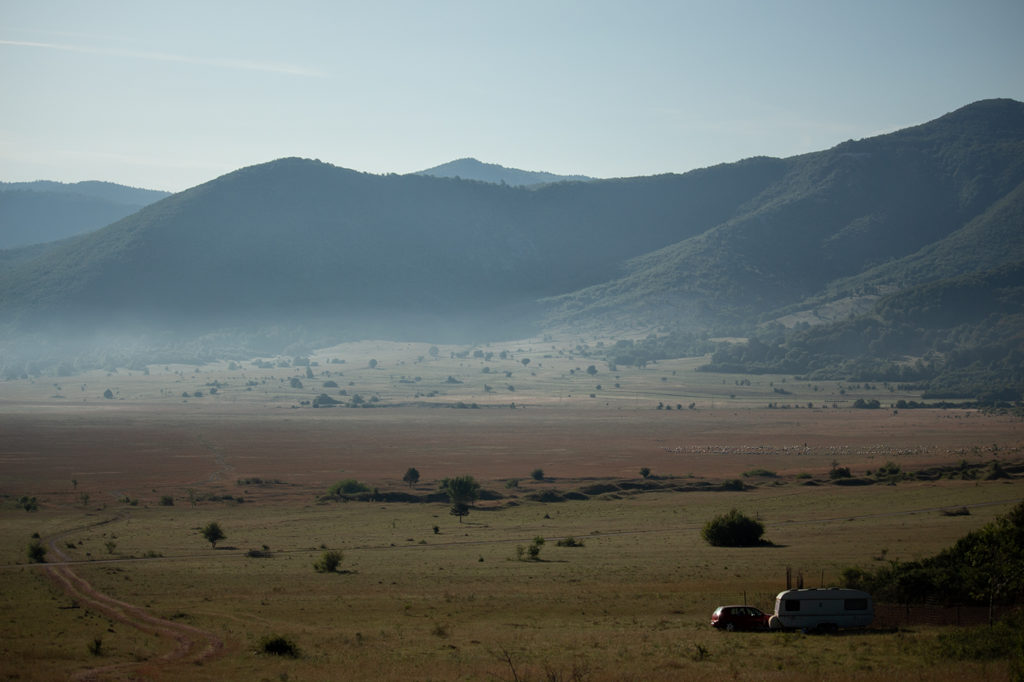 Nebelschleier über Hochland in Kroatien mit Wohnwagen und Schafherde