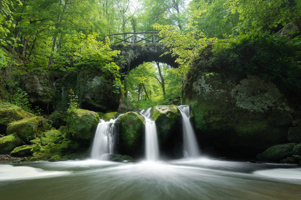 märchenhafter Wasserfall mit drei Flüssen und Brücke darüber