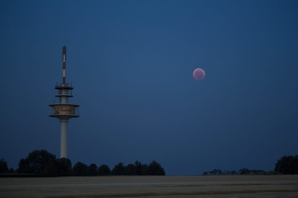 Fernmeldeturm Ober-Olm zur blauen Stunde mit rotem Vollmond rechts neben dem Turm; Fernsehturm