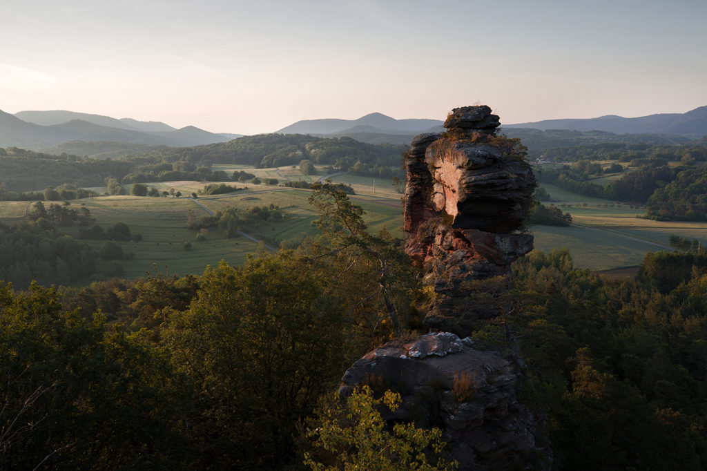 Von Sonne Angestrahlter Luger Geierstein mit Landschaft im Hintergrund bei Sonnenaufgang