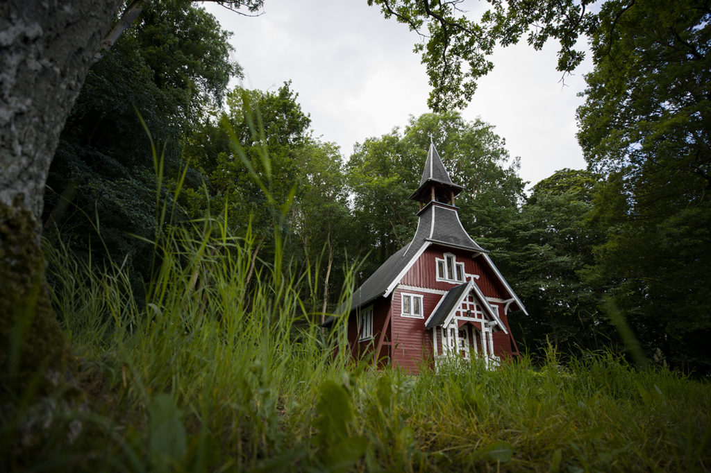 Rot Weiße Holzkapelle aus der Froschperspektive mit grünem Gras im Vordergrund