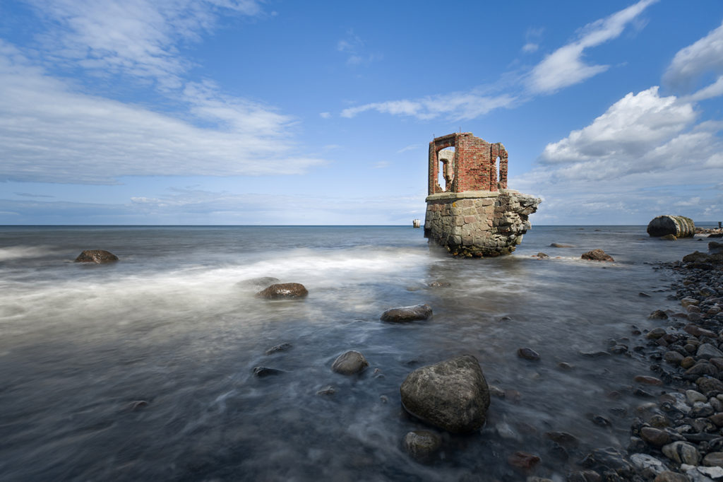 Alte Pegelhaus Ruine aus Backstein steht in bewegungsunscharfen Wellen an der Küste