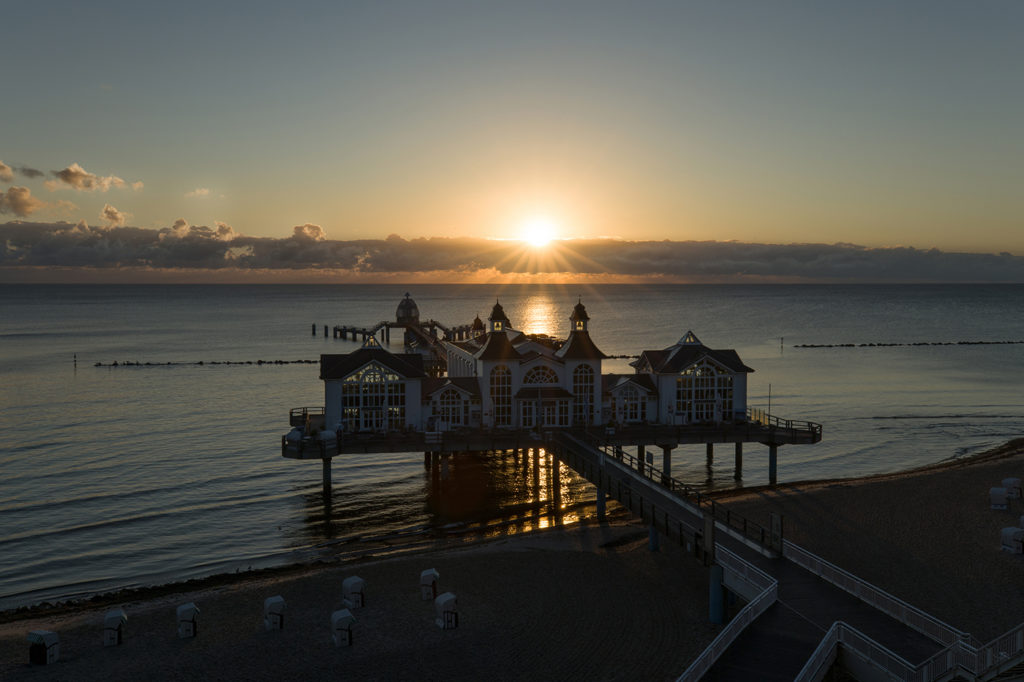 Selliner Seebrücke mit Sonnenaufgang über Wolkenschicht dahinter