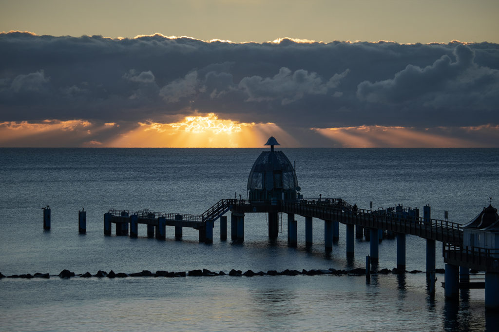 Selliner Tauchglocke bei Sonnenaufgang mit hinter Wolken raus brechenden Sonnenstrahlen